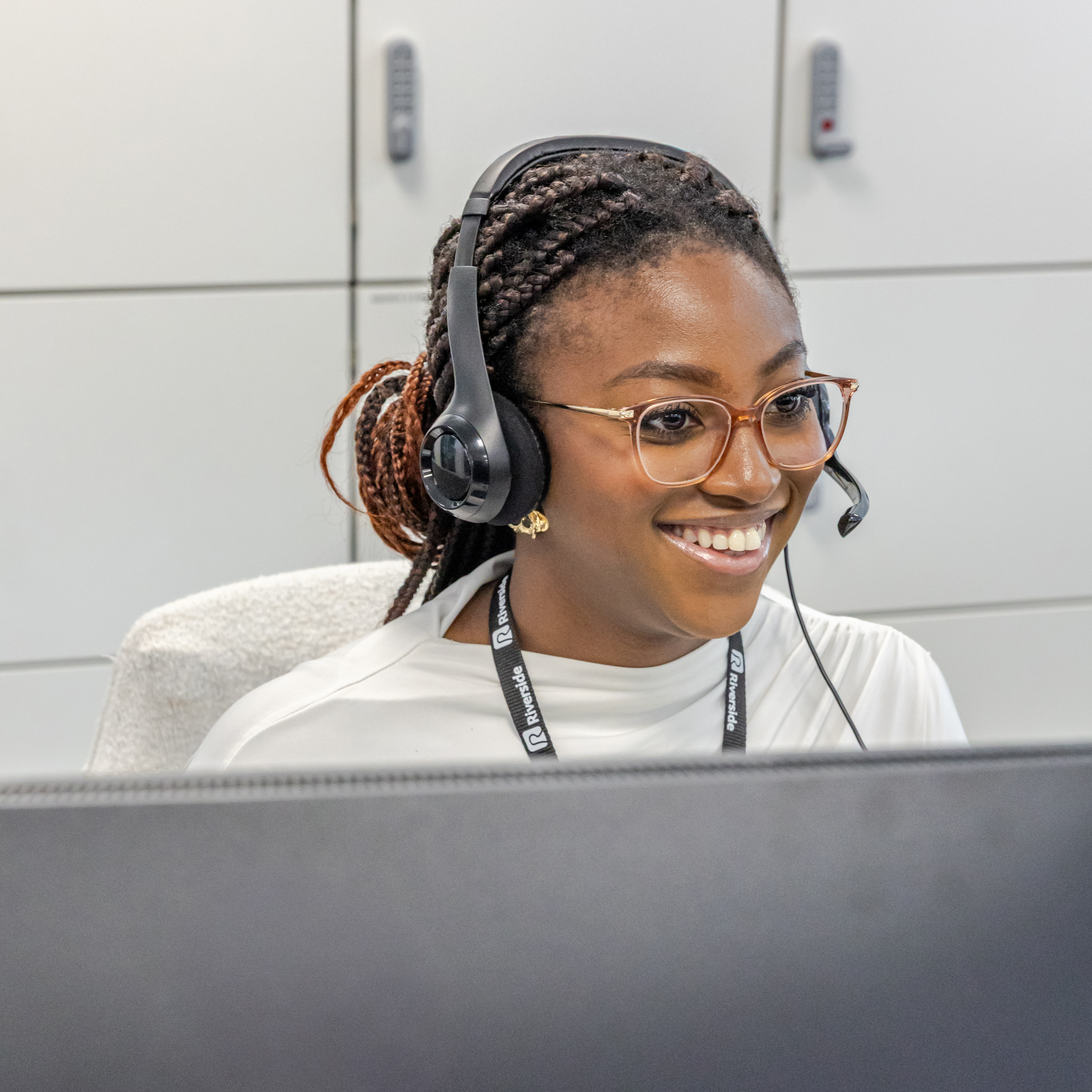 A person sits at a computer wearing a headset