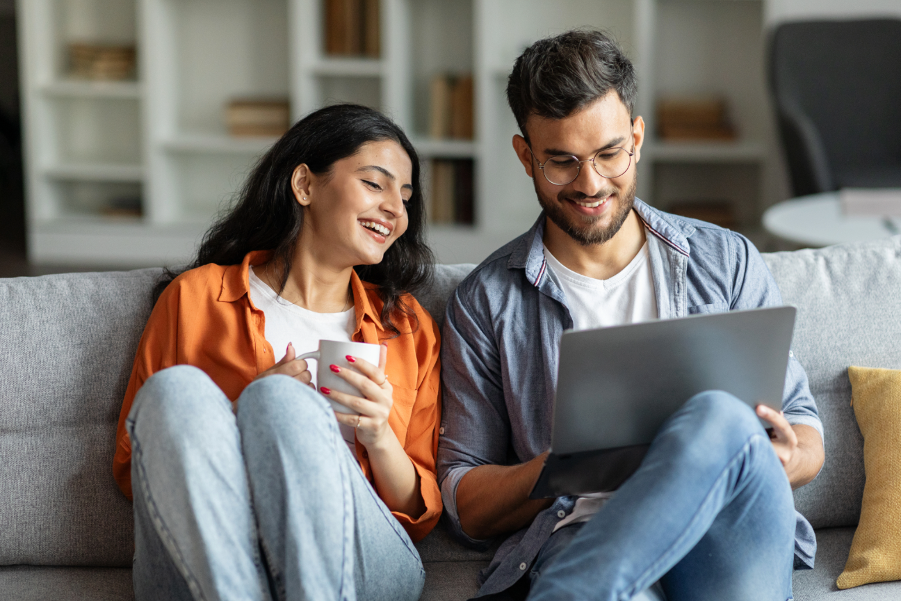 young couple sitting on sofa with laptop